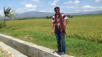 Djarot berpose dengan latar belakang gunung dan sawah.