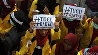 Massa berorasi dengan membawa atribut aksi seperti poster.