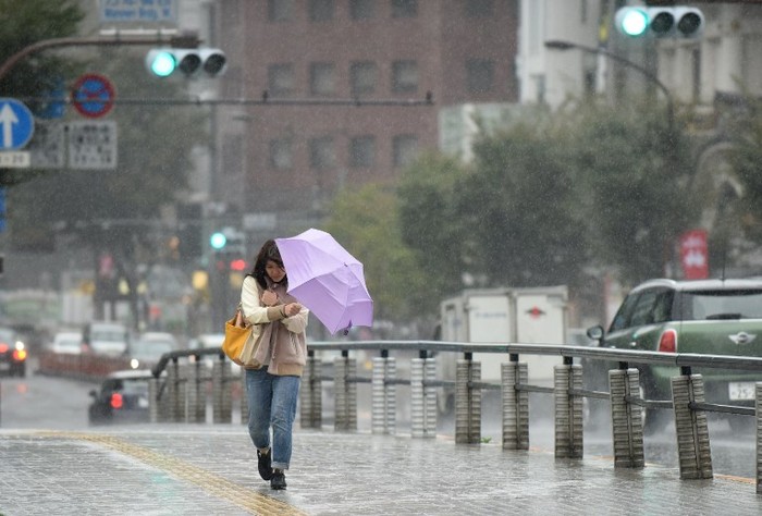 A woman have an umbrella turned inside out with strong wind in Tokyo on October 22, 2017. 
A powerful typhoon barrelled toward Japan on October 22, with heavy rain triggering landslides and delaying voting at one ballot station as millions struggled to the polls for a national election.  / AFP PHOTO / Kazuhiro NOGI