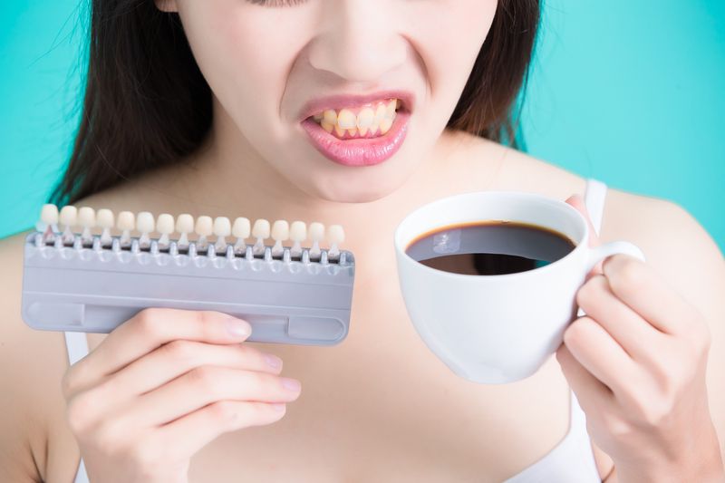 Woman holding cigarettes with yellow teeth isolated on blue background, asian
