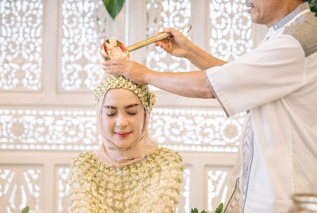 Saat sesi siraman sebelum menikah dengan putra dari almarhum penyanyi dangdut senior, Fazal Dath, Hamidah Rachmayanti cantik dalam balutan kerudung krem. Meski menggunakan melati di atas kepalanya namun ia tetap memakai jilbab yang dililitkan secara sederhana tak hanya menggunakan ciput. Foto: Dok. Instagram @imagenic