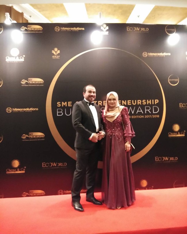 Siti Nurhaliza tampil feminin mengenakan dress berpayet warna merah marun. Lihat bagian lengannya, aksen ruffle memberikan detail yang atraktif. Perut hamilnya tidak terlihat mengenakan baju tersebut. Siti Nurhaliza berpose bersama sang suami tercinta, Datuk Seri Khalid. Foto: Dok. Instagram @ctdk