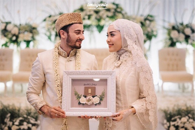 Hamidah Rachmayanti menikah dengan Irvan Farhad di Rancamaya Golf & Country Club, Bogor, Sabtu (21/10/2017). Ketika akad nikah, baik selebgram 23 tahun ini dan pria yang dikabarkan pernah dekat dengan penyanyi dangdut Cita Citata itu mengenakan baju bernuansa putih. Hamidah memilih gaya hijab yang sederhana tapi klasik. Foto: Dok. Instagram @imagenic