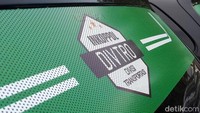 Di bagian belakang taksi online tertempel stiker berwarna hijau bertuliskan Inkopol Divtro (Divisi Transportasi).