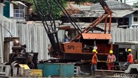 Petugas dengan bantuan alat berat memasang beton untuk turap.