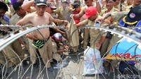 Mereka yang berada di baris terdepan dan berhadapan langsung dengan kawat berduri membuka bajunya untuk dibakar.