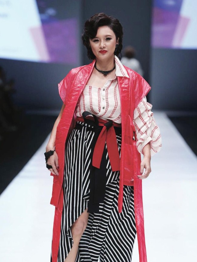 Dengan bibir berona merah, ibu dua anak ini menebar pesonanya dalam balutan blus longgar dan rok bertumpuk yang hadir dengan belahan tinggi di depannya. (Foto: Instagram/the_theme_ig)