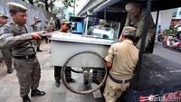 Petugas Satpol PP membawa gerobak Pedagang Kaki Lima (PKL) saat menggelar razia di kawasan kawasan Kuningan, Jakarta Selatan. 