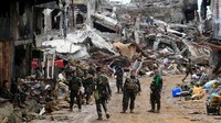 Sejumlah tentara Filipina berjalan di depan bangunan yang hancur