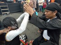 Seorang pawang berusaha menyadarkan penari yang kesurupan