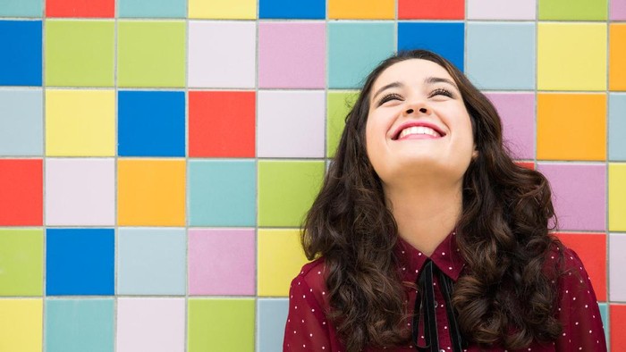 Happy girl laughing against a colorful tiles background. Concept of joy