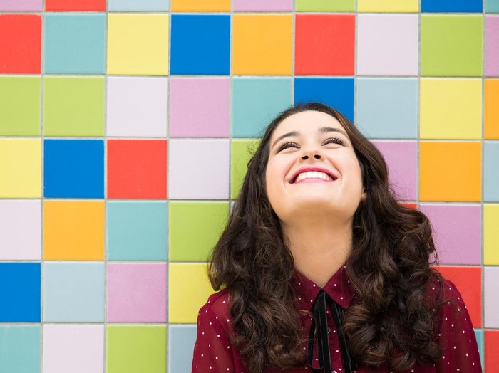 Happy girl laughing against a colorful tiles background. Concept of joy