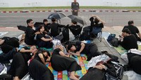 Para warga yang berpakaian serba hitam itu menyelimuti diri mereka dengan jas hujan dan membawa payung untuk melindungi diri dari hujan.
