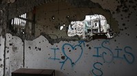 Ada grafiti bertuliskan I love ISIS di salah satu bangunan yang hancur.