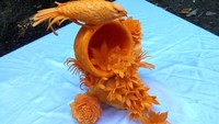 Wah, ternyata labu kuning juga bisa ya dipahat dengan bentuk burung yang sedang hinggap di tumpukan bunga.