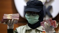 Petugas KPK menunjukkan barang bukti uang pecahan Rp 100 ribu.