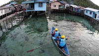 Dua orang petugas menaiki sampan menuju rumah-rumah penduduk di Pulau Natuna. Pool/Agus Trimukti/Humas PLN.