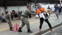 Seorang PKL berusaha lari dari kejaran petugas saat tertangkap menjajakan barang dagangannya di jalur pedestrian depan Stasiun Tanah Abang.
