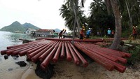 Petugas PLN mengangkut tiang-tiang listrik yang telah terkumpul di pinggir pantai di Pulau Natuna. Pool/Agus Trimukti/Humas PLN.