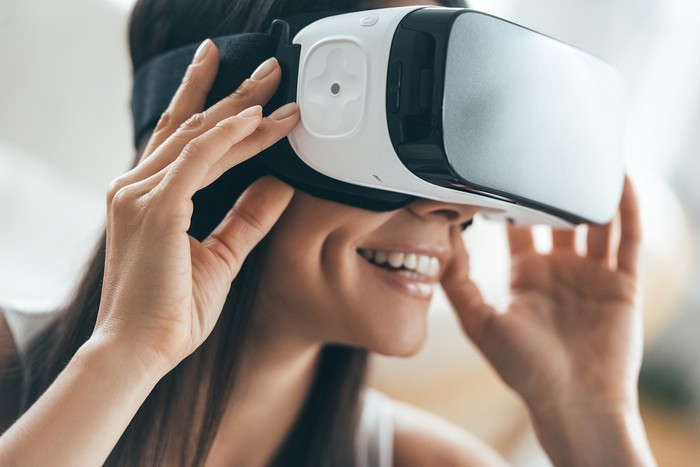 Attractive young woman adjusting her VR headset and smiling while sitting at home