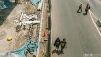 Pejalan kaki terpaksa membahayakan diri dengan berjalan di jalan raya karena jalan pedestrian belum rampung.