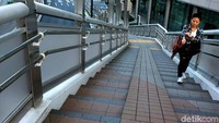 Seorang warga melintas di jembatan penyeberangan yang bersih di kawasan Ginza.