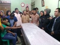 Suami Titik (kaos hijau) menunggui jenazah istrinya