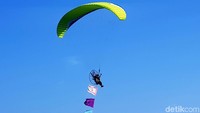 Seorang anggota Saka Bahari Malang menumpang paramotor mengibarkan bendera pramuka di langit Pasir Putih.
