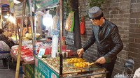 Seperti contohnya pedagang pria ini yang berjualan memakai kopiah. Dia berjualan kuliner lokal yang halal (Elvan/detikTravel)