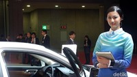 Model berdiri di samping mobil Lexus.