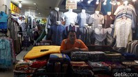 Seorang pedagang pakaian menunggu calon pembeli.