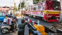 Sebuah kereta melintas di Perlintasan sebidang di Jalan KH Mas Mansyur.