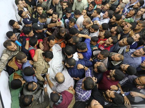 Warga mengangkat jasad warga Palestina yang terbunuh di dekat perbatasan antara Israel dan Jalur Gaza