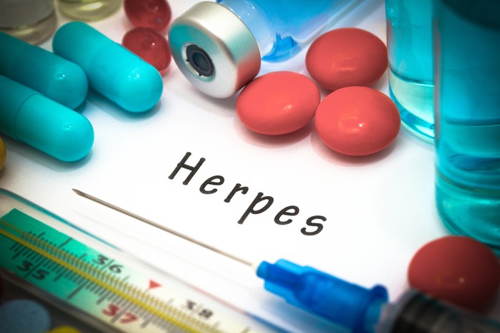 herpes Herpes - diagnosis written on a white piece of paper. Syringe and vaccine with drugs.