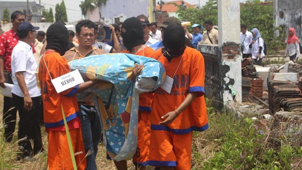 Para tersangka menggendong korban untuk dimasukkan ke sumur