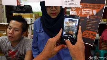 Pengunjung mengabadikan tata cara registrasi kartu prabayar yang terpampang di gerai SIM Card.