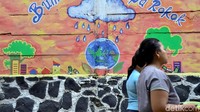 Mural bumi sehat tanpa rokok menghiasi permukiman warga di bantaran kali tersebut.