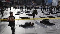 Seorang perempuan memegang gambar ayam mati di samping orang-orang yang tergeletak ini. (Foto: AFP PHOTO / JACQUES DEMARTHON)