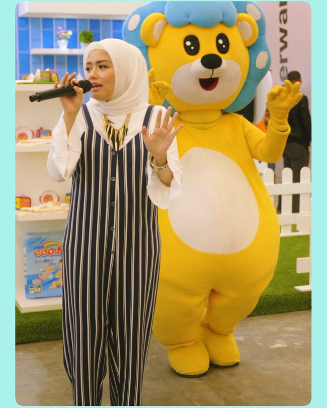 Ini momen ketika Tika Ramlan menyanyi setelah berhijab. Ia memilih jumpsuit berkancing dengan garis vertikal agar tubuhnya terlihat lebih kurus. Padu padan blouse putih, kerudung off white, dan kalung statement memberikan sentuhan yang atraktif.  Foto: Dok. Instagram @tika_ramlan