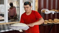 Seorang tukang roti mempersiapkan adonan roti untuk dipanggang.