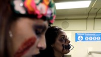 Para zombie berjalan di jalanan ibu kota. Pulasan make up mereka mirip sekali dengan penampakan zombie seperti yang biasa dilihat di film. 