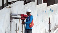 Seorang pekerja mengebor dinding velodrome.
