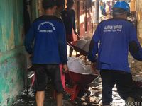 Petugas membawa karung pasir untuk menyumbat air