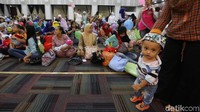 Seorang ibu memapah bayinya berjalan sambil menunggu giliran dipijat.