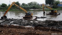 Pekerja mengeruk lumpur yang mengendap di Kanal Banjir Barat.