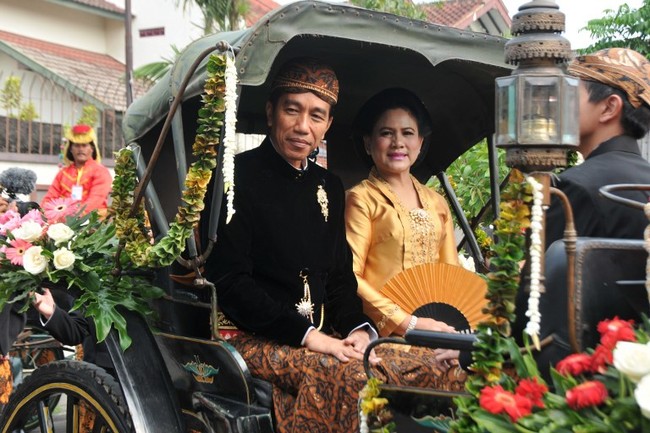 Iriana tampak memadukan kain batik Sidomulyo itu dengan kebaya kutu baru nuansa emas, sementara Jokowi memakai beskap beludu hitam. Foto: AFP PHOTO / ANWAR MUSTAFA