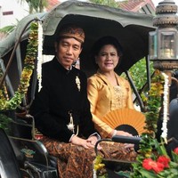 Iriana tampak memadukan kain batik Sidomulyo itu dengan kebaya kutu baru nuansa emas, sementara Jokowi memakai beskap beludu hitam. Foto: AFP PHOTO / ANWAR MUSTAFA