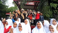 Warga melambaikan tangan kepada calon mempelai yang mengikuti prosesi kirab.
