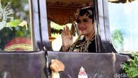 Kahiyang tersenyum sambil melambaikan tangan kepada warga di sepanjang jalan yang dilintasi dalam prosesi kirab.