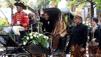 Jokowi melambaikan tangan kepada warga di sepanjang jalan yang dilintasi iring-iringan kereta kencana.